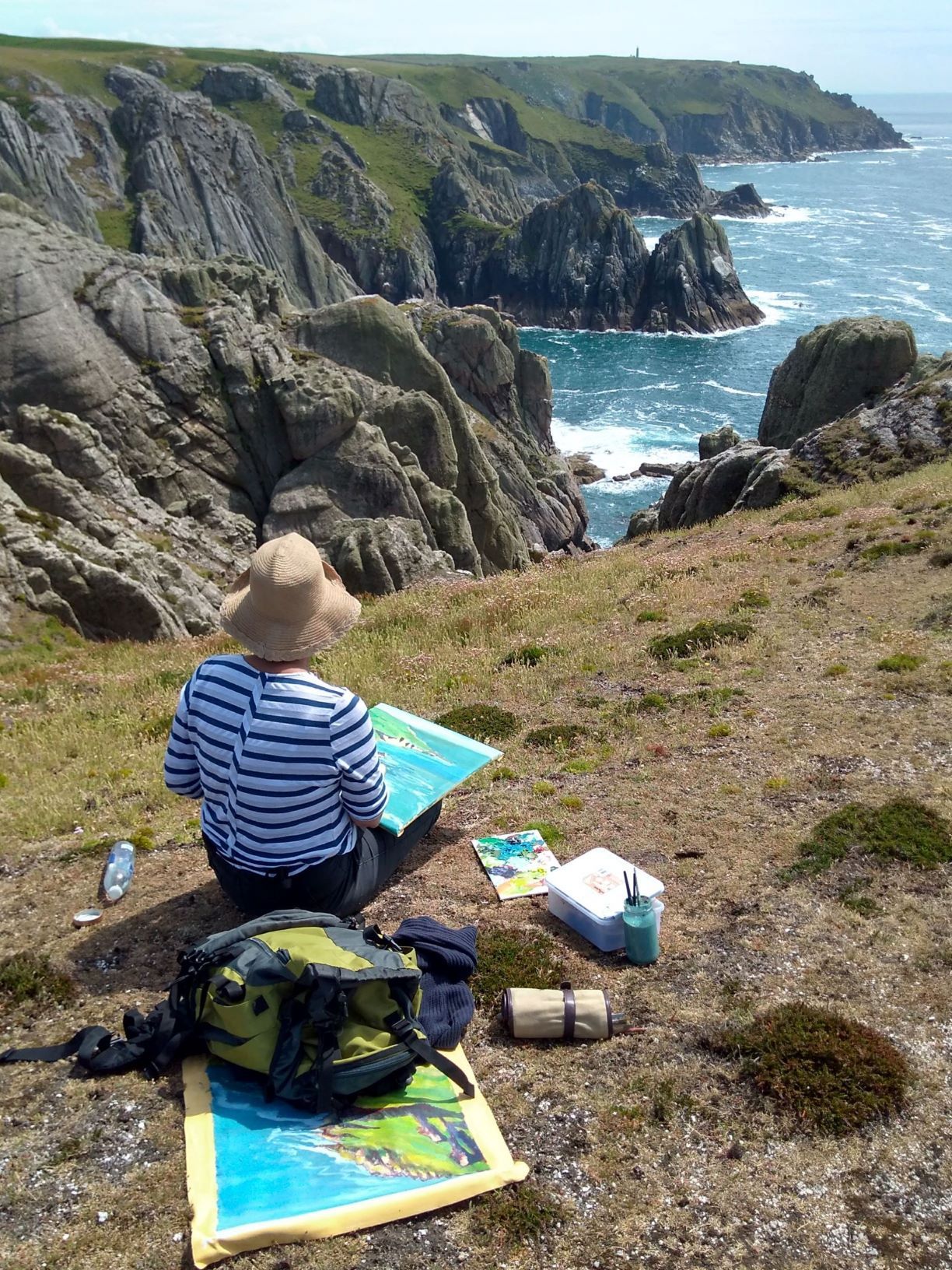 Annie painting seascapes outdoors on Lundy Island looking out at the sea and the cliffs.